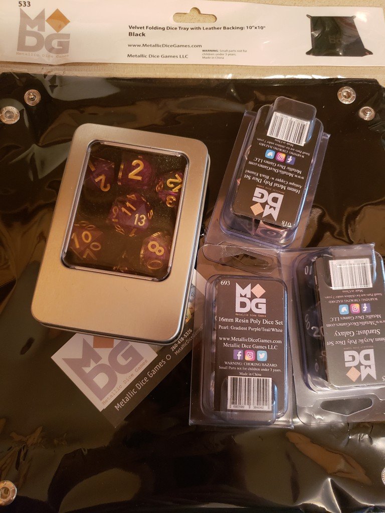 ALl four sets of dice and the dice tray in their packaging. The hand crafted dice come in their own metal carrying case.